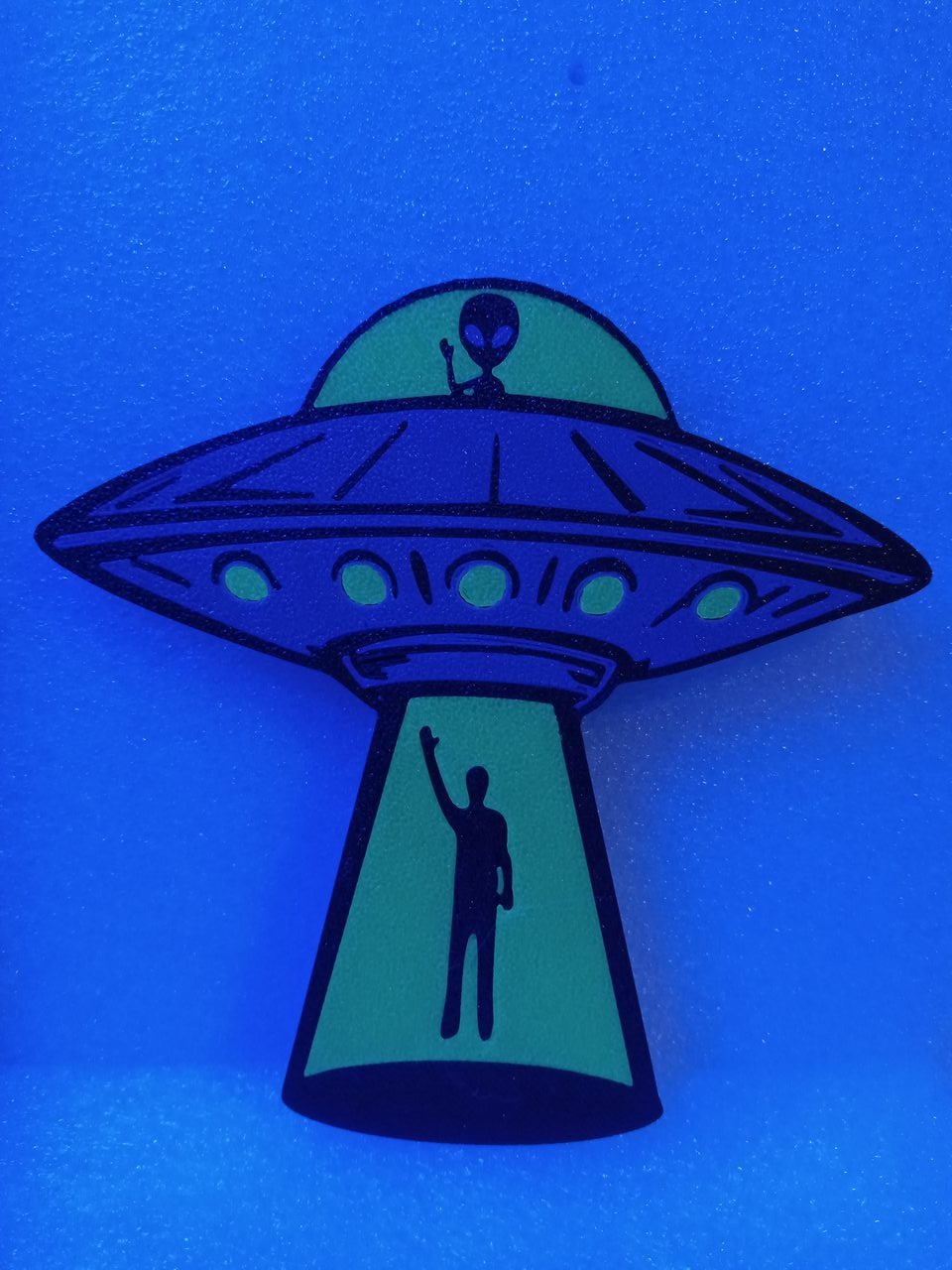 The same Glow Ships keychain glowing in the dark under UV light